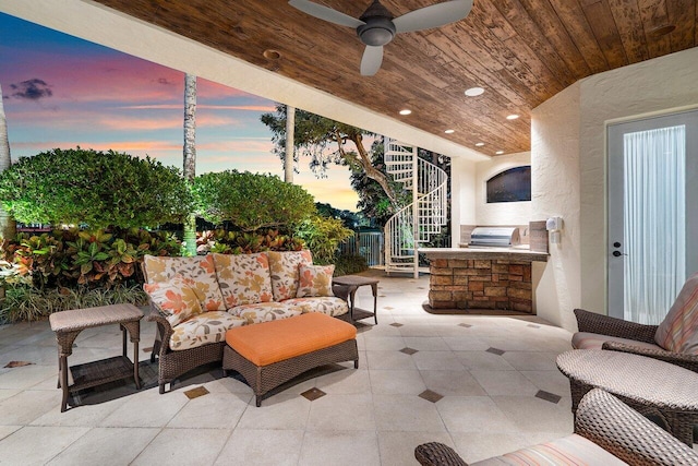 patio terrace at dusk with exterior kitchen, ceiling fan, and outdoor lounge area