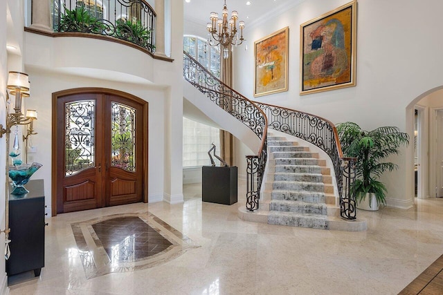 entrance foyer with ornamental molding, french doors, a chandelier, and a high ceiling