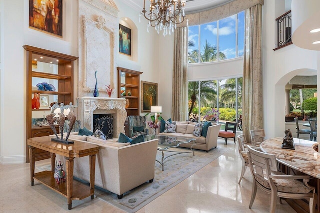 living room featuring a towering ceiling, ornamental molding, an inviting chandelier, and a premium fireplace