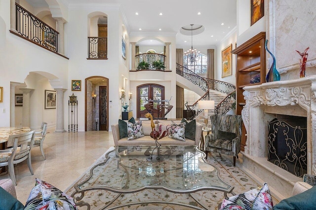 living room featuring ornamental molding, a premium fireplace, an inviting chandelier, and a high ceiling