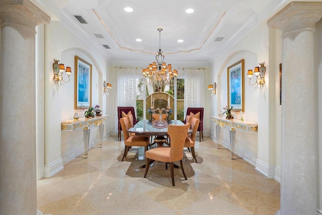 dining space with a raised ceiling, crown molding, a notable chandelier, and ornate columns