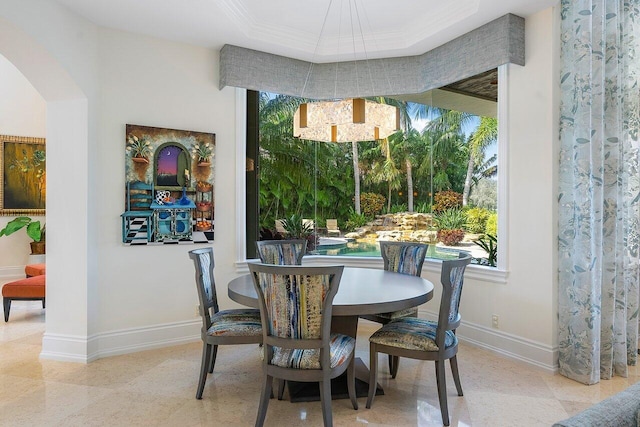 dining area with ornamental molding, an inviting chandelier, and a tray ceiling