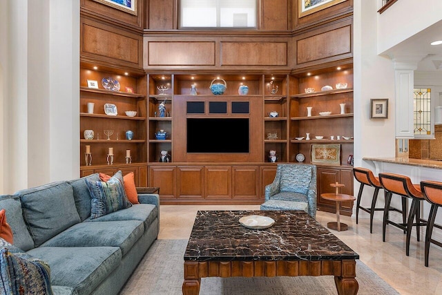 living room with built in features, ornate columns, and a high ceiling