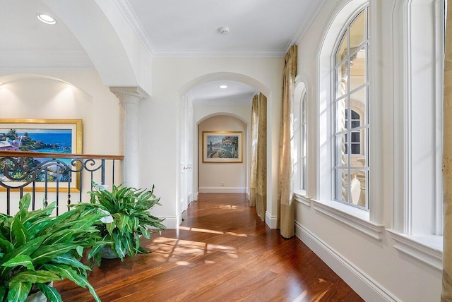 corridor with dark wood-type flooring, ornamental molding, and decorative columns