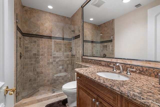 bathroom with a shower with door, vanity, and toilet