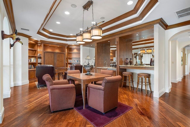 dining space with built in features, dark hardwood / wood-style floors, a raised ceiling, and crown molding