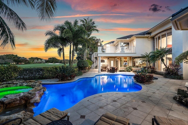 pool at dusk with a patio area