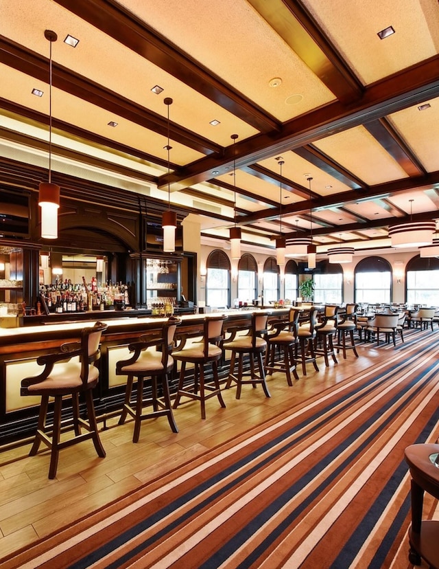 dining area with bar, coffered ceiling, hardwood / wood-style flooring, and beamed ceiling