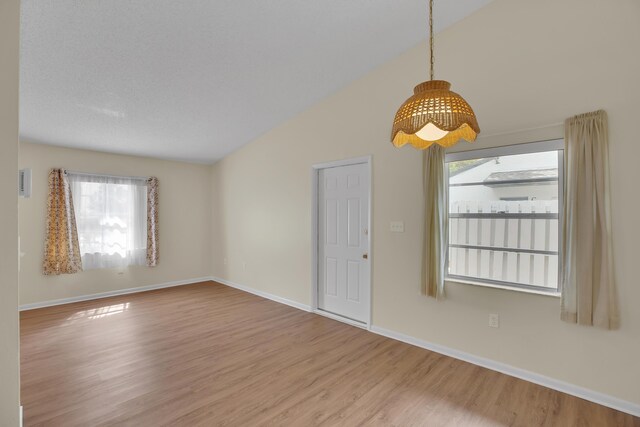 unfurnished room with a wealth of natural light, hardwood / wood-style flooring, and lofted ceiling