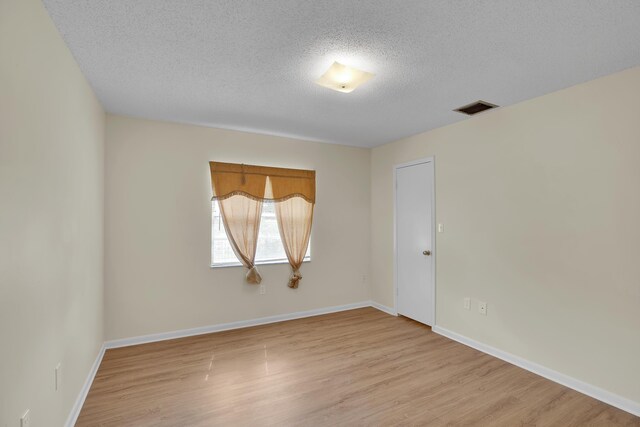 spare room with a textured ceiling and light hardwood / wood-style flooring