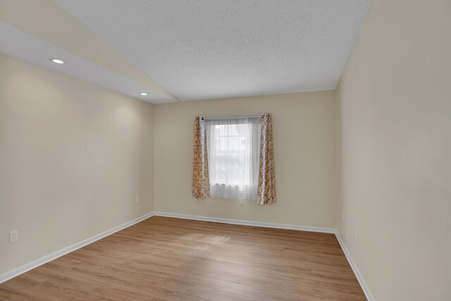 spare room with a textured ceiling and wood-type flooring