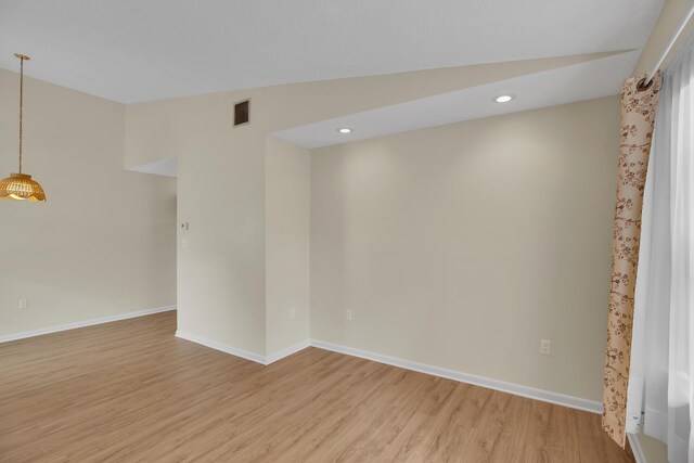 unfurnished room featuring lofted ceiling and hardwood / wood-style floors