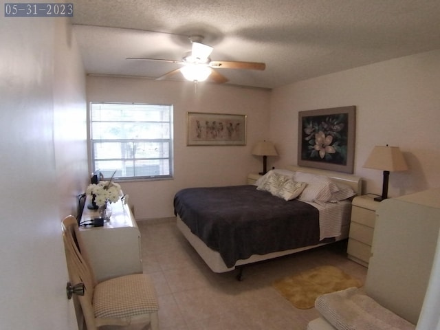 tiled bedroom featuring ceiling fan and a textured ceiling