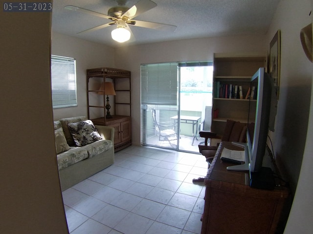 interior space featuring light tile patterned floors, a textured ceiling, and ceiling fan