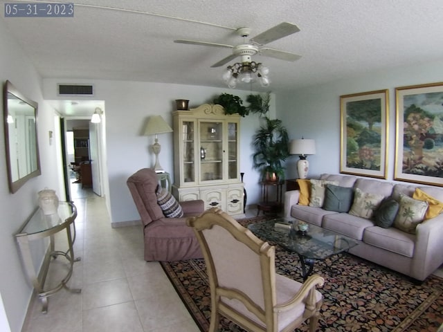 living room with ceiling fan, light tile patterned floors, and a textured ceiling