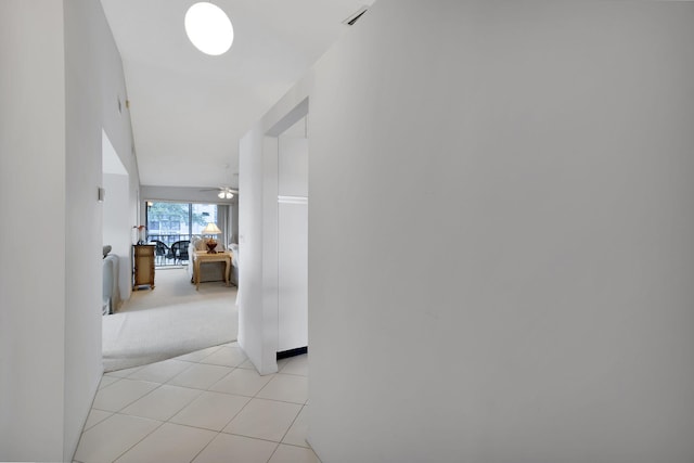 corridor with light tile patterned flooring, light colored carpet, and visible vents