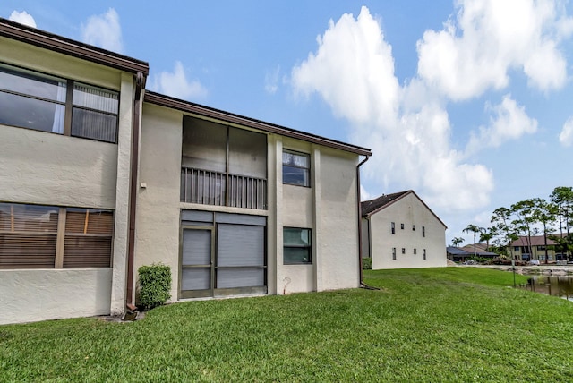 back of property with a lawn and stucco siding