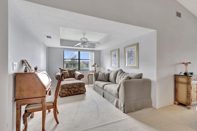 living room with visible vents, a raised ceiling, light carpet, and ceiling fan