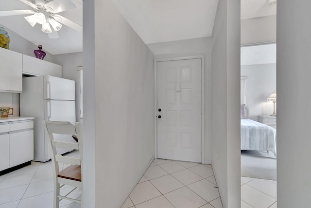 interior space featuring light countertops, light tile patterned flooring, white cabinets, and freestanding refrigerator