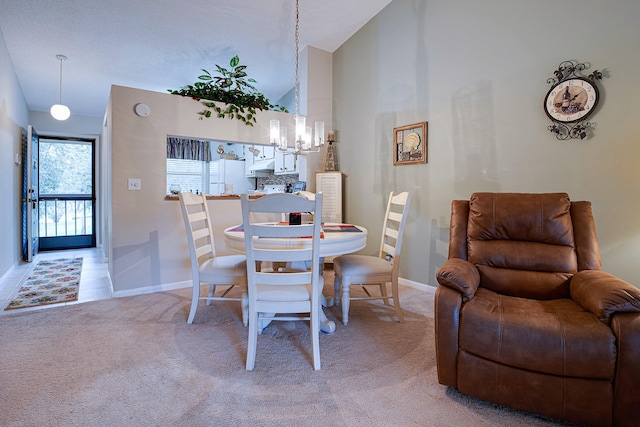 carpeted dining space with high vaulted ceiling and a chandelier