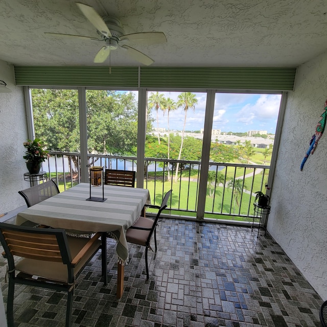 sunroom / solarium featuring a water view and ceiling fan