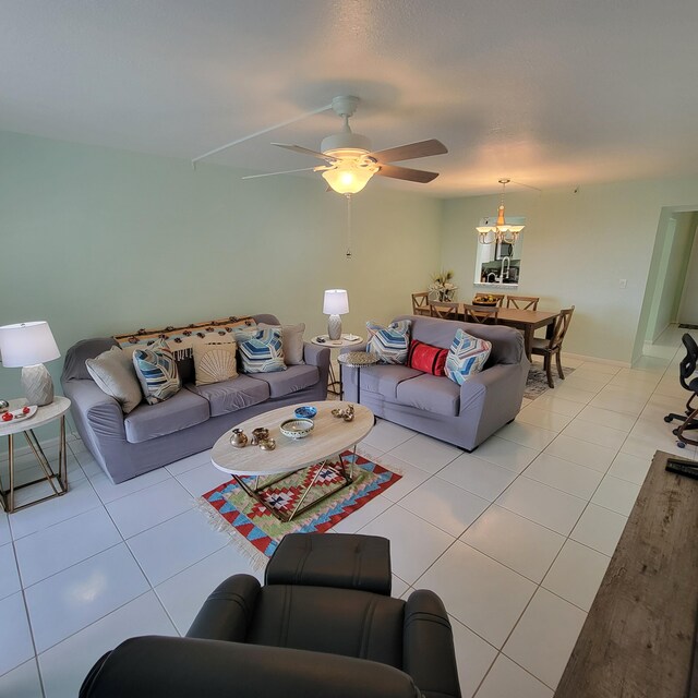 tiled living room with ceiling fan with notable chandelier