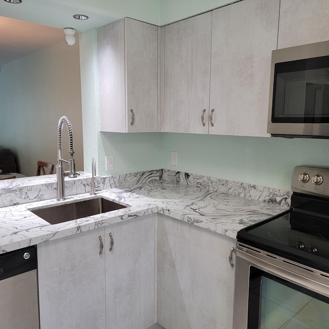 kitchen with light stone countertops, stainless steel appliances, sink, and tile patterned flooring