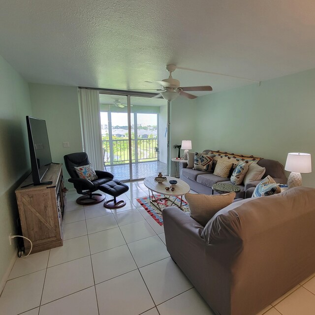 tiled living room featuring a textured ceiling, ceiling fan, and a wall of windows