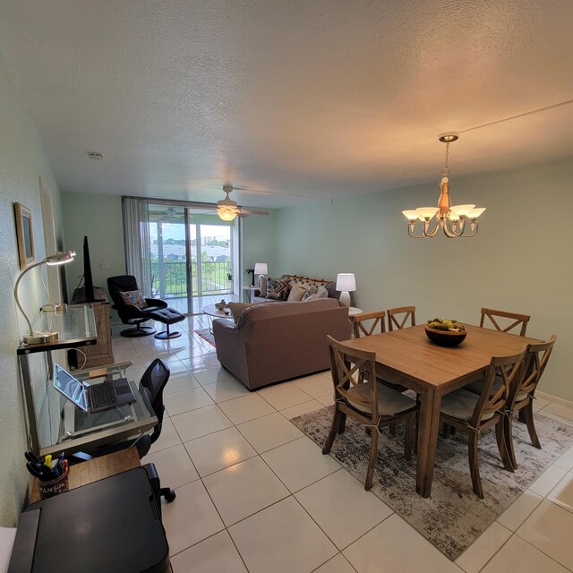 tiled dining space with a textured ceiling, floor to ceiling windows, and ceiling fan with notable chandelier