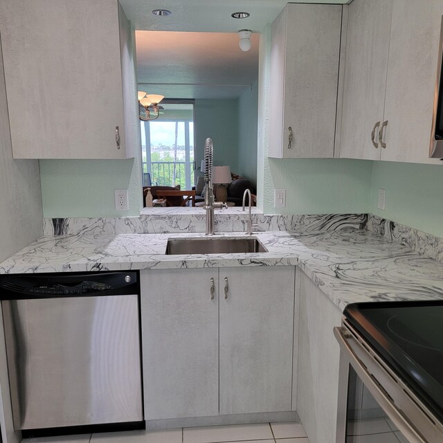 kitchen with light stone counters, sink, light tile patterned flooring, and stainless steel dishwasher