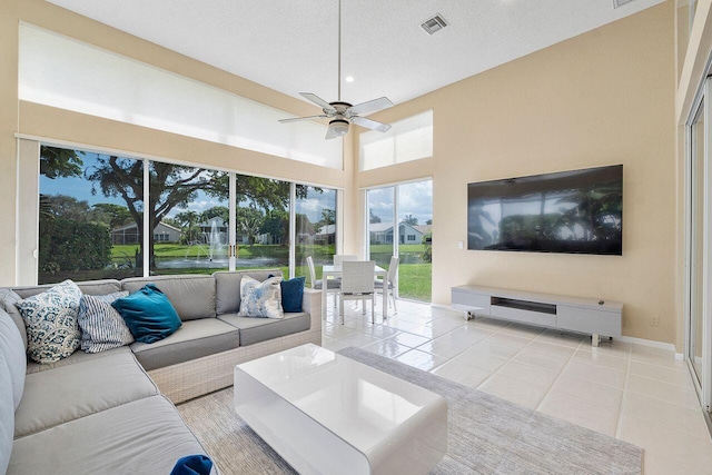 living room featuring a textured ceiling, ceiling fan, and light tile patterned floors