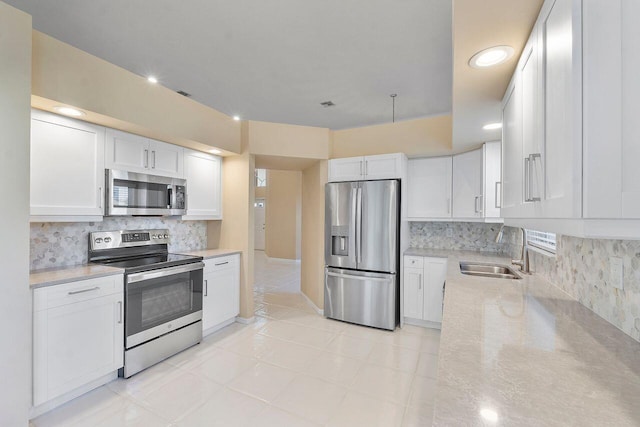 kitchen with white cabinetry, sink, stainless steel appliances, and light stone counters