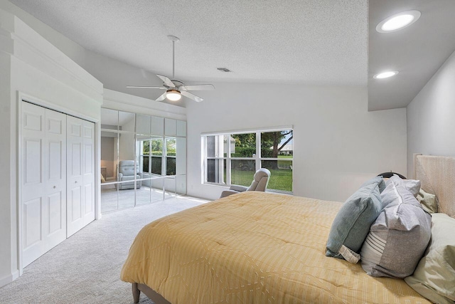 bedroom featuring a closet, a textured ceiling, vaulted ceiling, light colored carpet, and ceiling fan