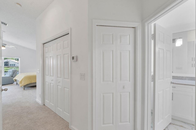 corridor with light colored carpet and a textured ceiling