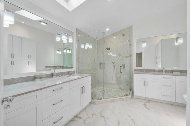 bathroom featuring a shower with door, vanity, and a skylight