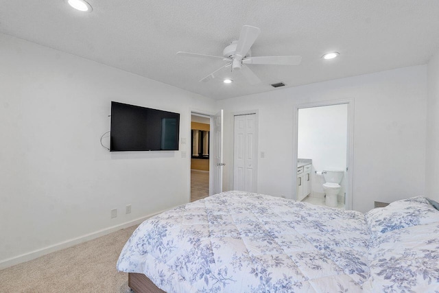 bedroom featuring ceiling fan, a textured ceiling, a closet, light carpet, and ensuite bathroom