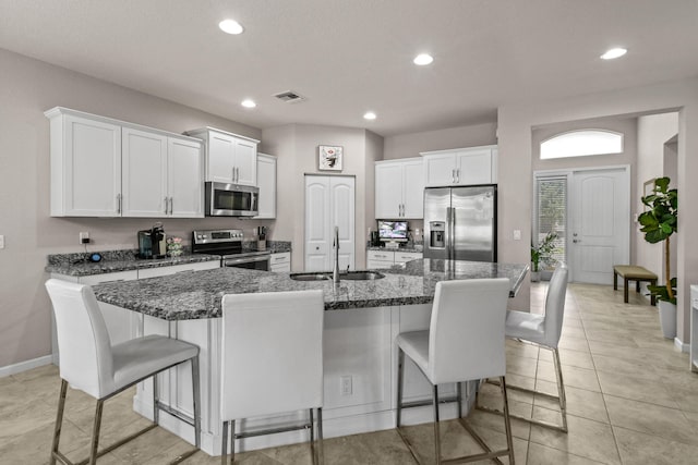 kitchen with appliances with stainless steel finishes, an island with sink, a breakfast bar, sink, and white cabinets