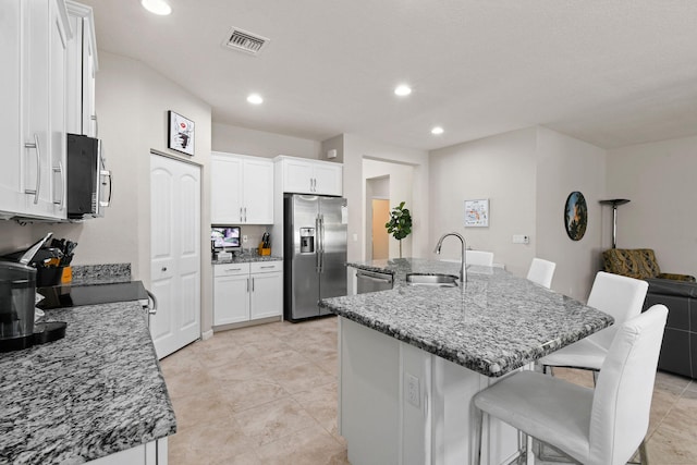 kitchen featuring a kitchen island with sink, stainless steel appliances, a kitchen breakfast bar, sink, and white cabinets