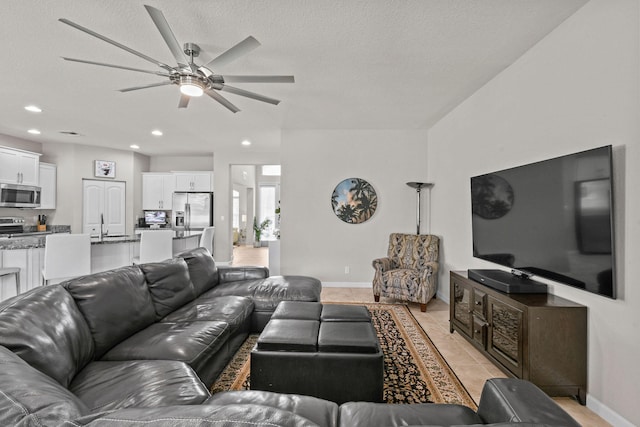 tiled living room featuring a textured ceiling, ceiling fan, and sink