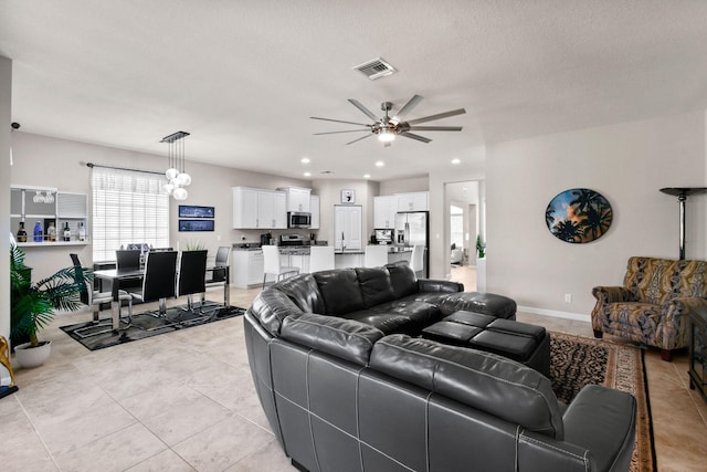 living room featuring ceiling fan with notable chandelier, a textured ceiling, and light tile patterned flooring