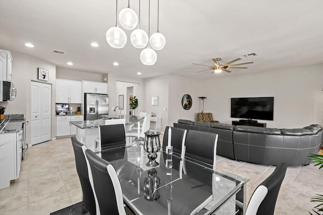 dining space with light tile patterned floors, sink, and ceiling fan