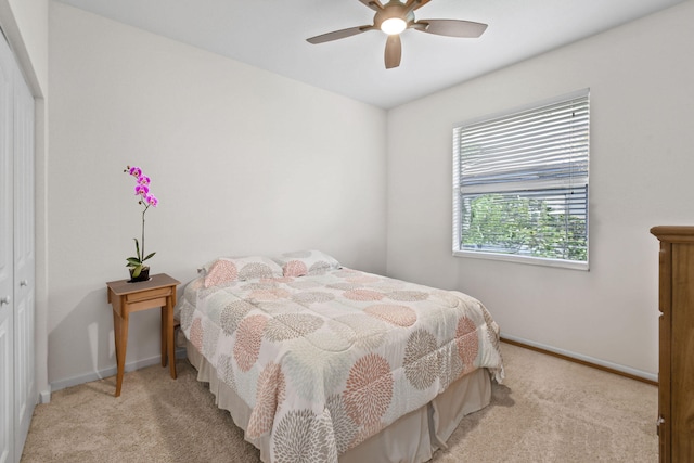 bedroom featuring light colored carpet, ceiling fan, and a closet