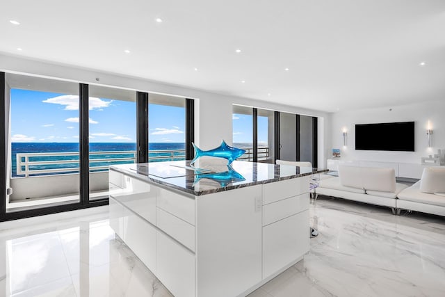 kitchen with white cabinetry, black electric stovetop, dark stone counters, and a kitchen island