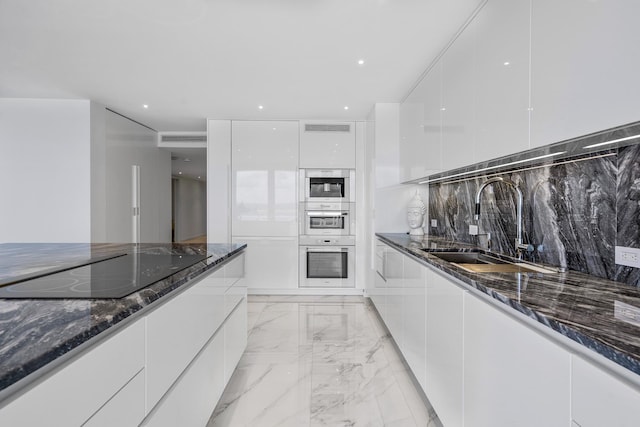 kitchen featuring white cabinetry, sink, dark stone countertops, decorative backsplash, and black electric stovetop