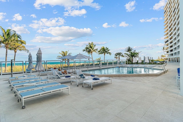 view of swimming pool featuring a water view and a patio area