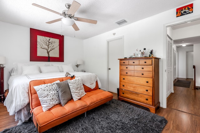 bedroom with a textured ceiling, wood-type flooring, ceiling fan, and a closet