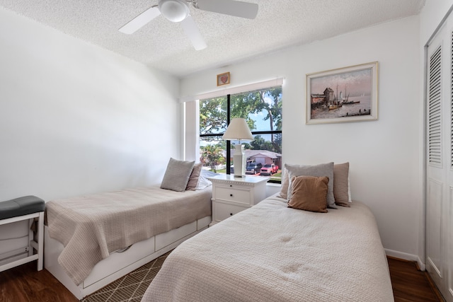 bedroom with a textured ceiling, dark hardwood / wood-style flooring, ceiling fan, and a closet