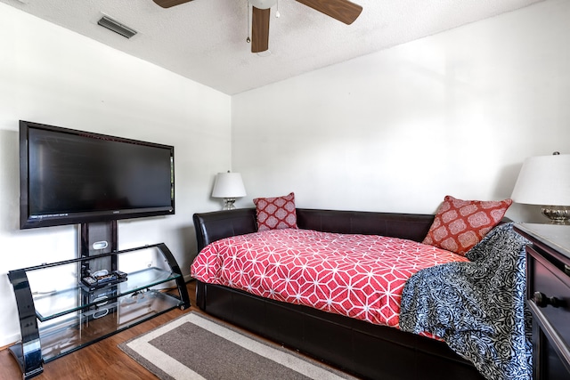 bedroom with a textured ceiling, ceiling fan, and wood-type flooring