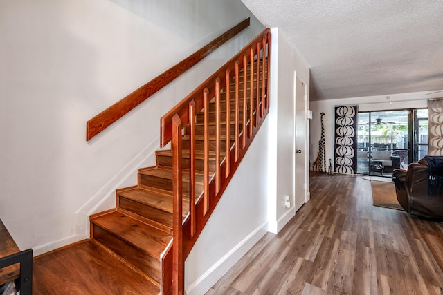 stairway with hardwood / wood-style flooring and a textured ceiling