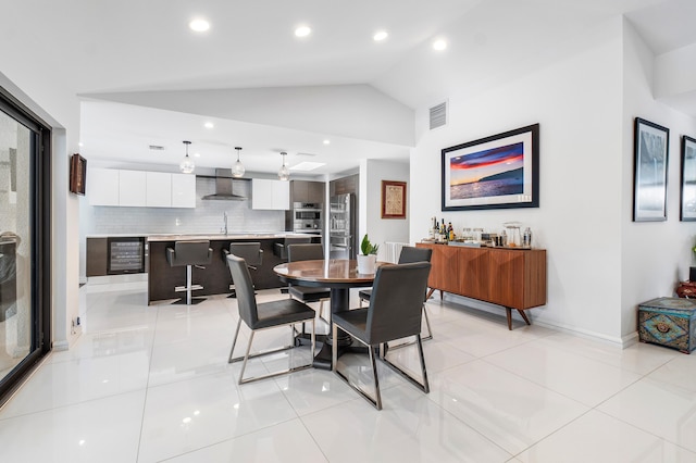 dining space featuring vaulted ceiling, sink, beverage cooler, and light tile patterned flooring